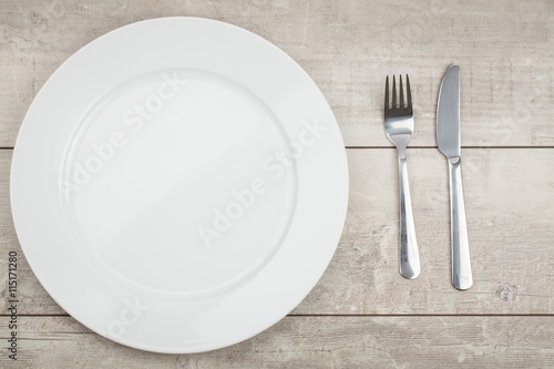 Empty Plate, Fork, Knife on wooden background. Top View with Text Space