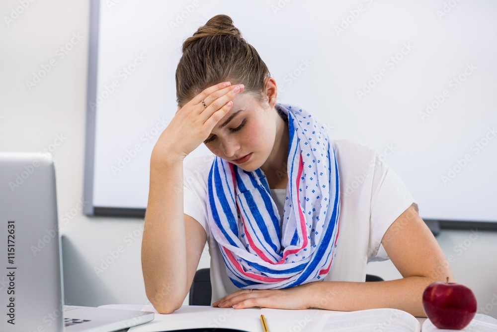Stressed teacher suffering from headache in classroom Stressed teacher suffering from headache in classroom