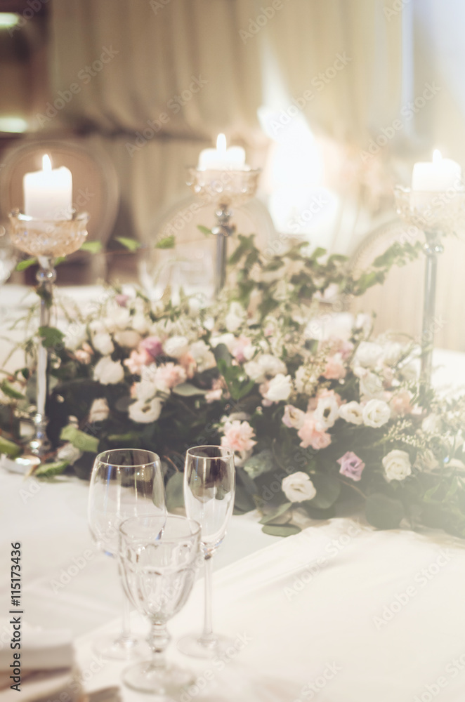 Wedding table set decoratet in banquet restoraunt. Floral composition beige, pink roses flowers, high candle coasters, glass goblets for wine. Atmosphere luxury. Text, free copy space. Wedding table set decoratet in banquet restoraunt. Floral composition beige, pink roses flowers, high candle coasters, glass goblets for wine. Atmosphere luxury. Text, free copy space.