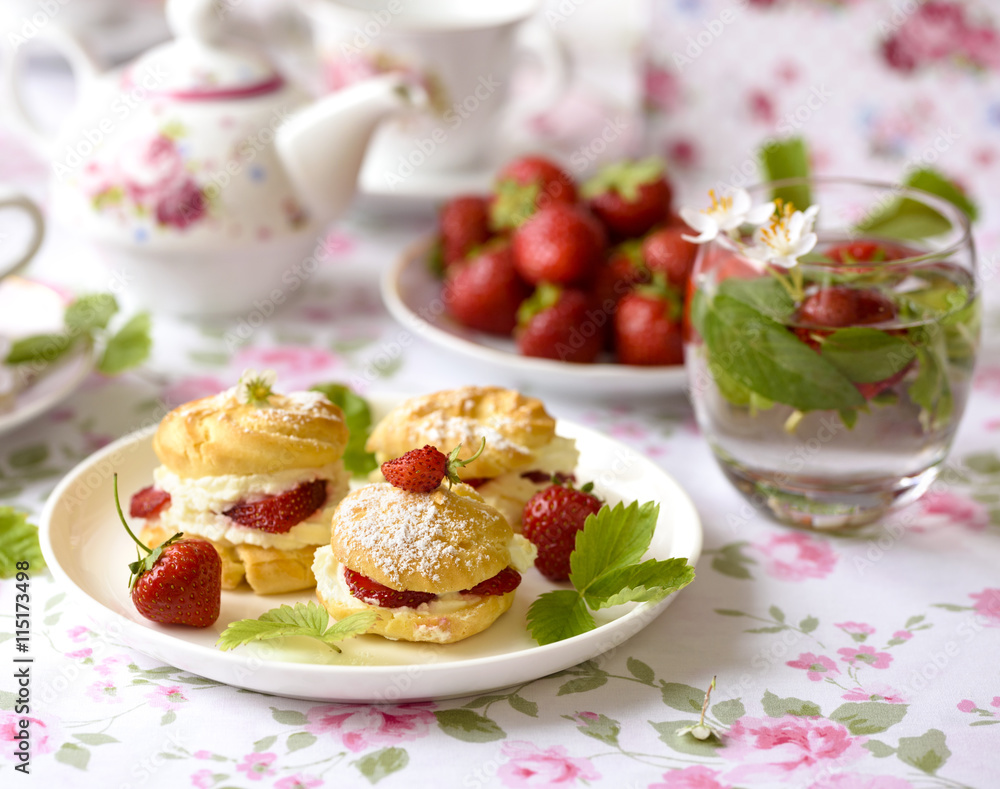 Cream puffs cakes or profiterole filled with whipped cream and served with strawberries on the table Cream puffs cakes or profiterole filled with whipped cream and served with strawberries on the table