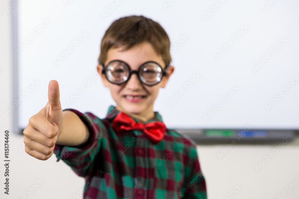 Boy gesturing thumbs up sign in classroom 