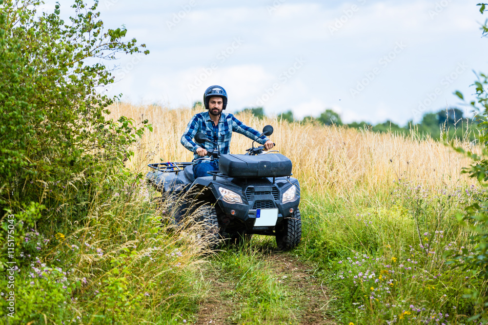 Mann fährt Off-Road mit Quad ATV durch Gelände Mann fährt Off-Road mit Quad ATV durch Gelände