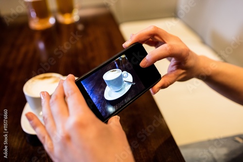 Woman photographing coffee cup on table