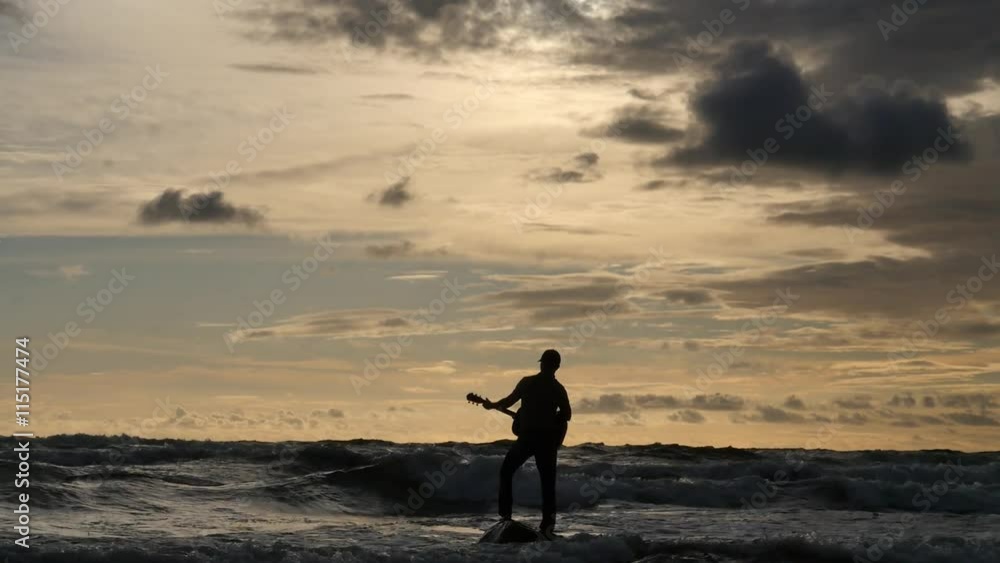 Silhouette of Man playing guitar on small rock in stormy sea - dolly shot Silhouette of Man playing guitar on small rock in stormy sea - dolly shot