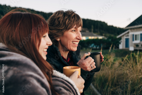 Mother and Daughter Drinking from Coffee Cups at Sunset