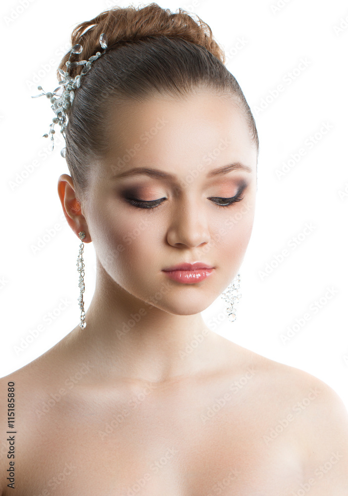 Portrait of a young girl with a wedding makeup. Perfect skin, smooth hair, large crystal earrings and hair ornament. Isolation on a white background.