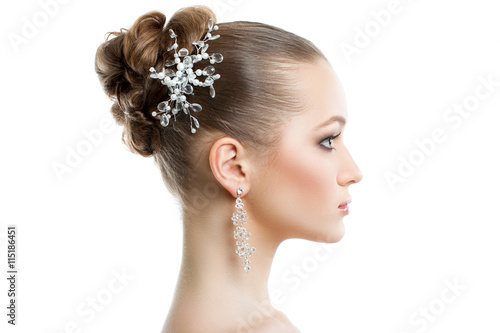 Beautiful female portrait in profile on a white background. Wedding makeup and jewelry, perfect skin, smooth hair.