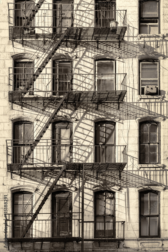 Fototapeta premium Typowy stary budynek w Nowym Jorku z drabinami przeciwpożarowymi (przetworzono antyczny wygląd)