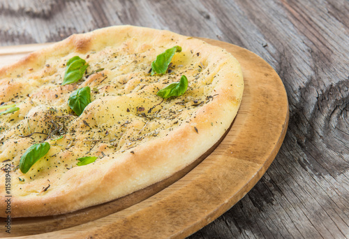 Quattro fromaggi pizza with basil on wooden table