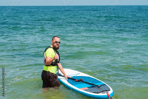 jolly man with a paddle floats on stand up paddle board on the s © serguastock