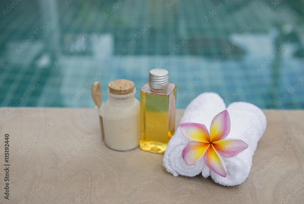 Spa concept background, white hand towel with plumeria flower at poolside Spa concept background, white hand towel with plumeria flower at poolside