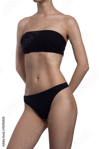 Slim body of the suntanned woman isolated on a white background. Black underwear. hands behind his back. Healthy lifestyle, Diets.