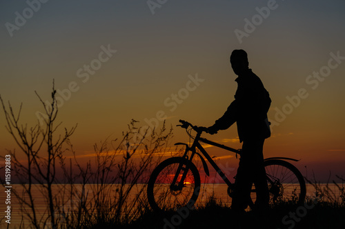 Dark silhouette of a cyclist on the beach