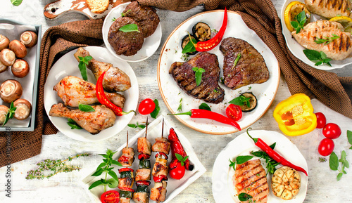 Assorted grilled meats and vegetables on wooden background.