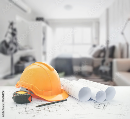 architectural blueprint with safety helmet and tools over bedroom with sofa as background