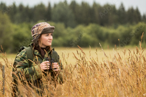 Leinwand Poster woman hunter, autumn rain, girl looks through binoculars