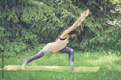 Woman doing yoga exercises outdoors in the city.Beautiful brunette fit young woman wearing sportswear practicing yoga urban style.Working out,fitness,sport,training and lifestyle concept