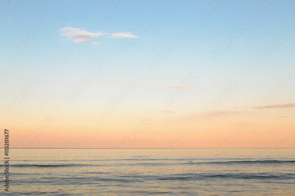 Fototapeta premium Still blue sea water under colorful evening cloudy sky