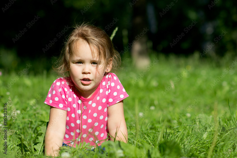 Девочка в парке лежит на траве, в платье в горошек