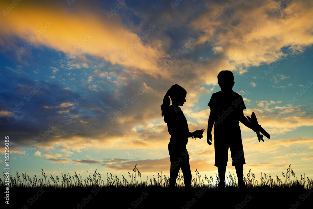 children qith kite and airplane at sunset