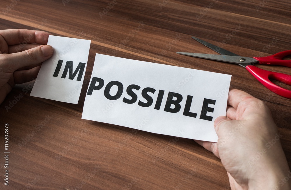 Possibility, success and challenge concept. Man is cutting paper with impossible word to make it possible. Possibility, success and challenge concept. Man is cutting paper with impossible word to make it possible.