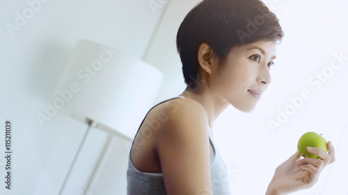 Wallpaper Mural Woman holding green apple in white room smiling happily Torontodigital.ca