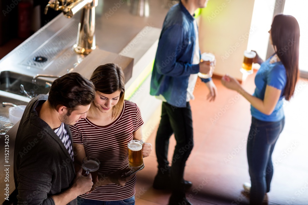 Woman showing mobile phone to boyfriend in bar