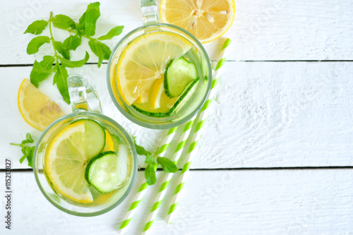 cold summer drink with lemon, mint and cucumber on a white backg