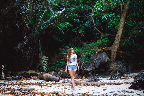 Young girl walking in tropical forest. Traveler lost in jungle photo