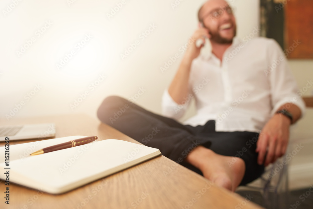 Diary on desk with businessman taking on phone