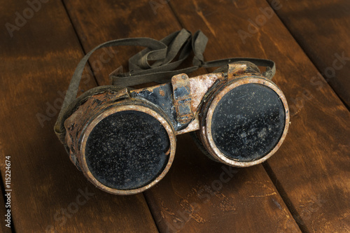 Old rusty steampunk goggles on wooden desk