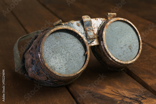 Old rusty steampunk goggles on wooden desk