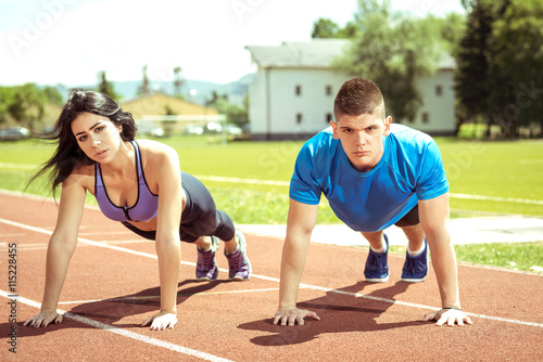 Young couple doing push ups on track.