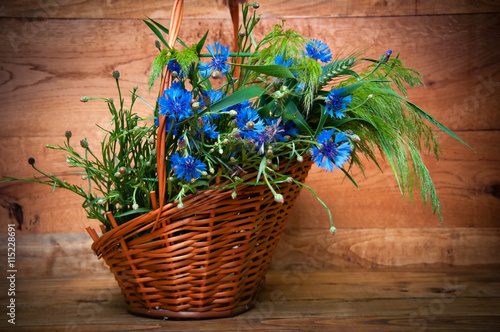 Cornflowers in basket on wooden background