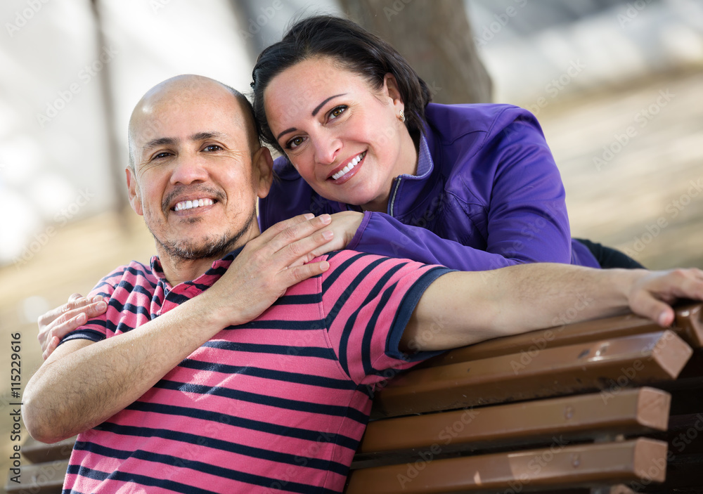 Happy smiling mature couple sitting on the bench and hugging each other.