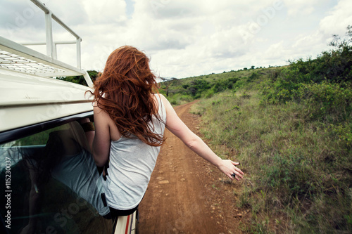 Woman sitting on door of vehicle in wildlife park, Nairobi, Kenya