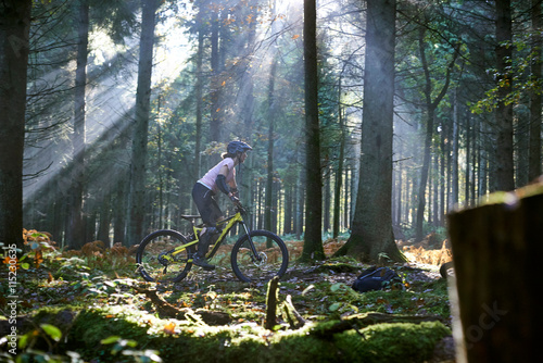 Female mountain biker cycling through sunbeam lit Forest of Dean, Bristol, UK photo