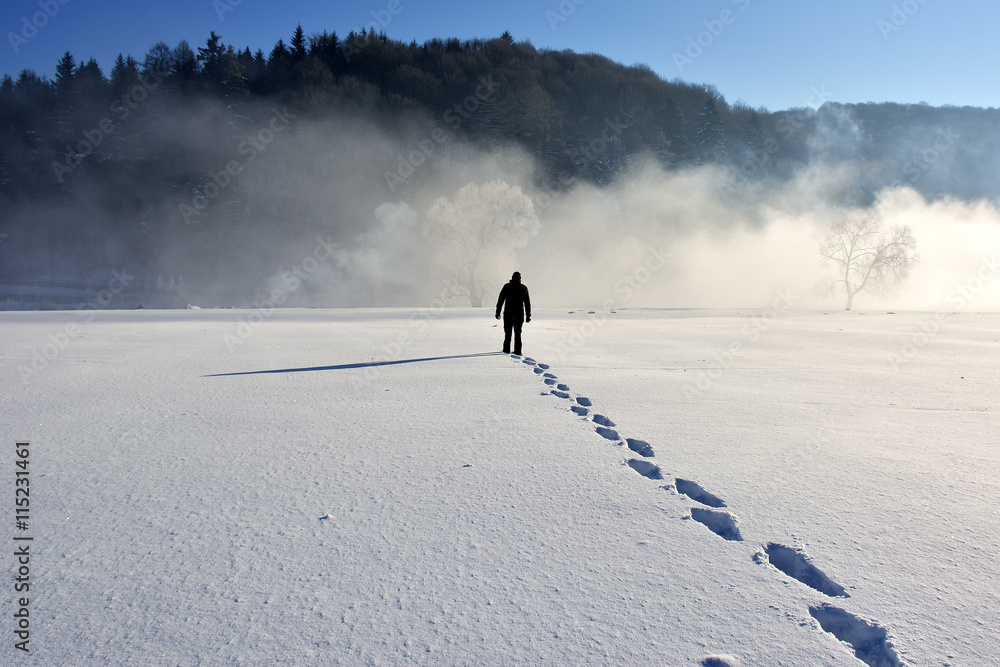 Obraz premium Man walking on snow, footprints in snow, behind