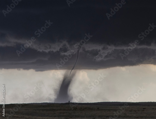  A needle shaped funnel reaches to the ground as this tornado forms over open country photo