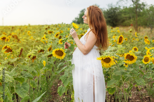 Pregnant woman in the field with sunflowers