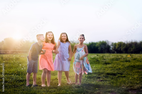 Children in field holding hands laughing photo