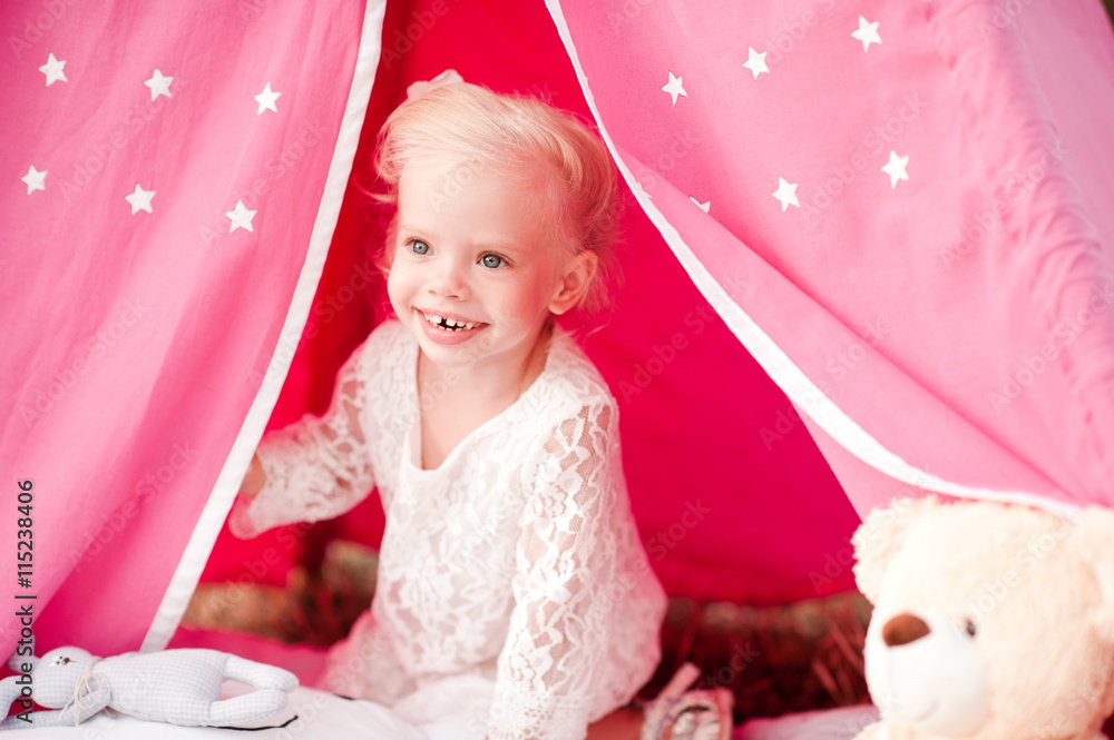 Fototapeta premium Smiling kid girl 3-4 year old sitting in tent outdoors