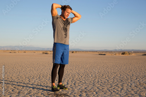 Man training, sweating with hands behind head on dry lake bed, El Mirage, California, USA photo