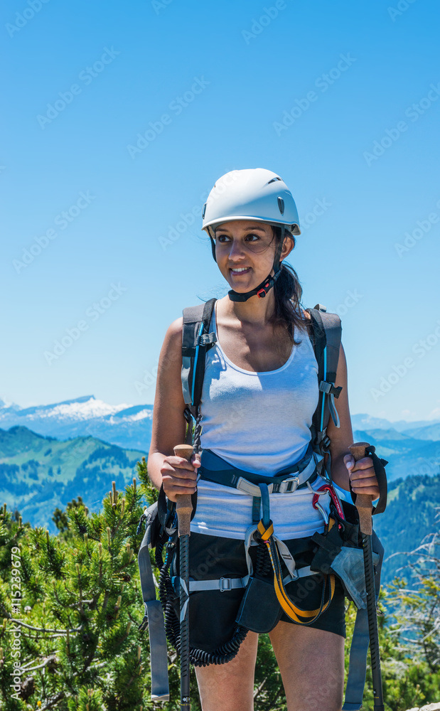 Smiling woman holding hiking sticks under blue sky Smiling woman holding hiking sticks under blue sky