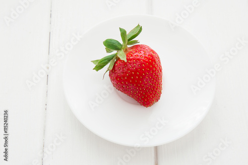 Fresh strawberry in white plate on the white wooden table