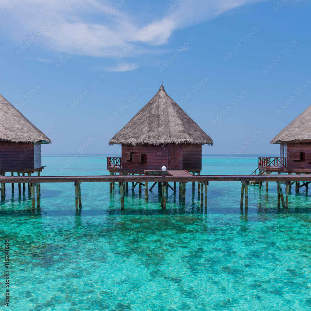 Honeymoon trip. Overwater  bungalows with stair descending into the sea. Turquoise color of the lagoon. Tropical island in the Indian Ocean. Luxury holiday.