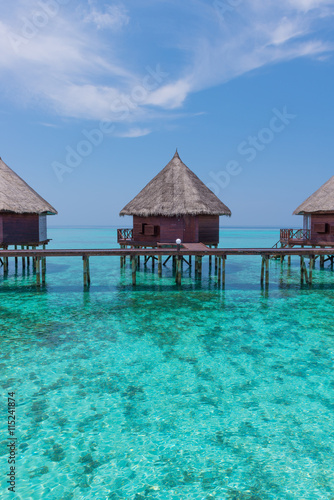 Honeymoon trip. Overwater bungalows with stair descending into the sea. Turquoise color of the lagoon. Tropical island in the Indian Ocean. Luxury holiday.