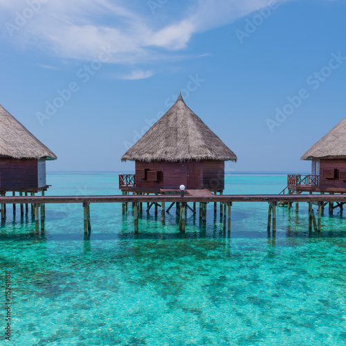 Honeymoon trip. Overwater bungalows with stair descending into the sea. Turquoise color of the lagoon. Tropical island in the Indian Ocean. Luxury holiday.