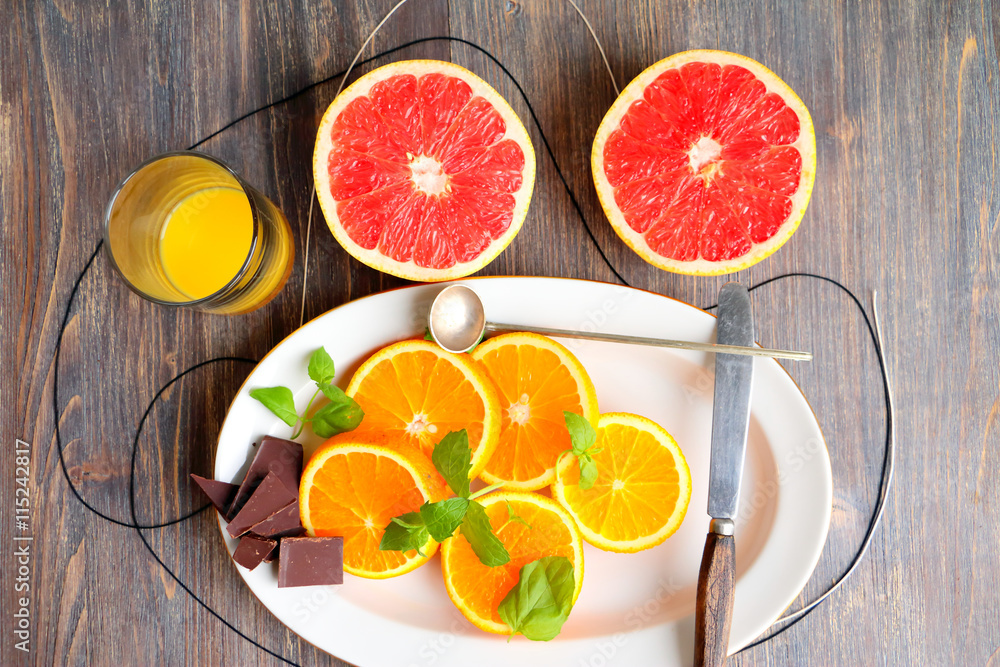 Grapefruit halves and orange slices with mint leaves and chocolate and creamy dessert on a wooden table
Grapefruit halves and orange slices with mint leaves and chocolate and creamy dessert on a wooden table
