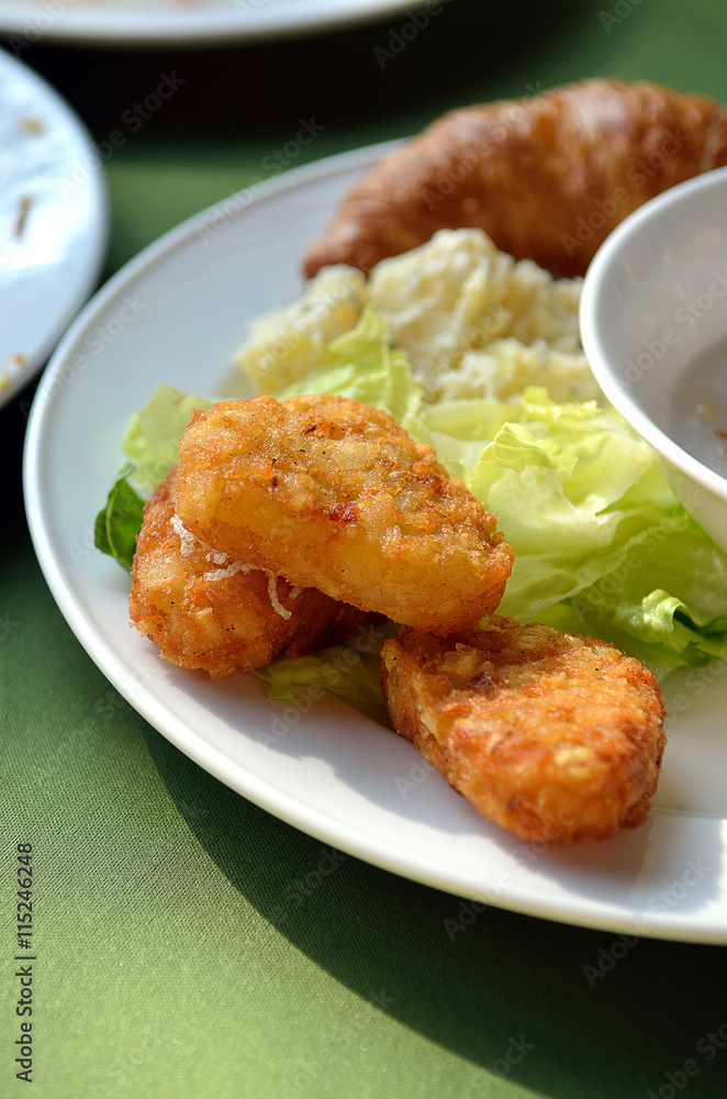 chicken nuggets and vegetable salad on a white plate.. chicken nuggets and vegetable salad on a white plate..